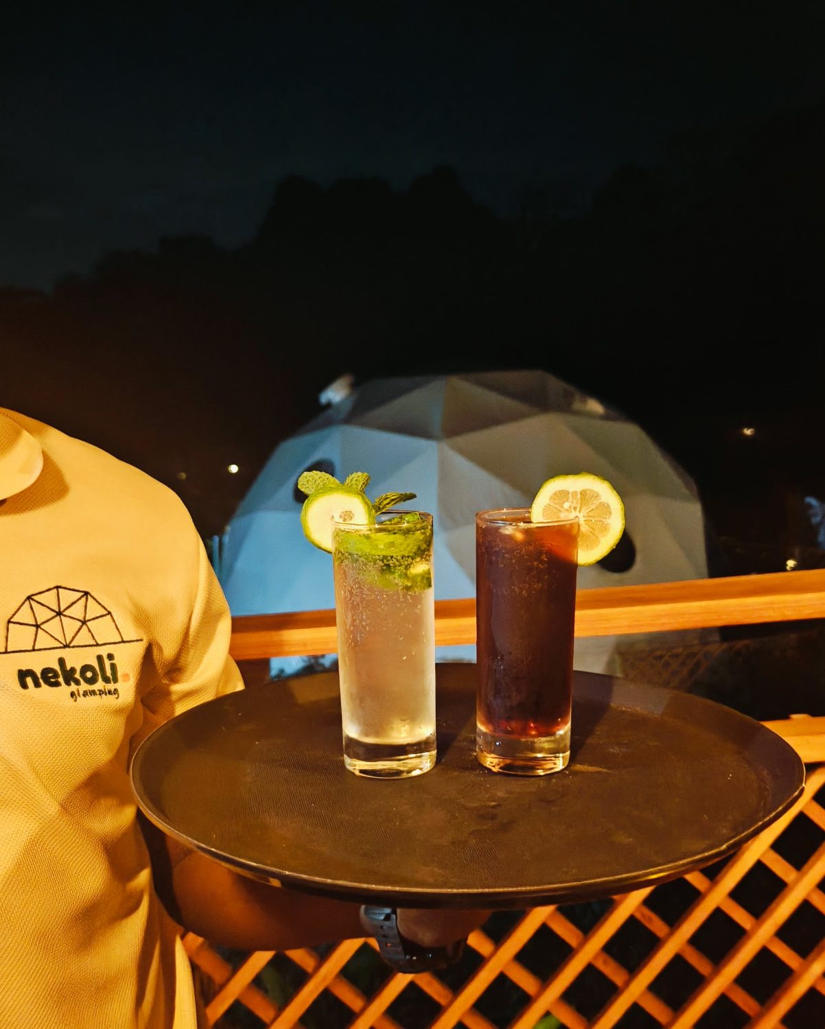 Two cocktails on the bar table after dark, a dome glowing behind
